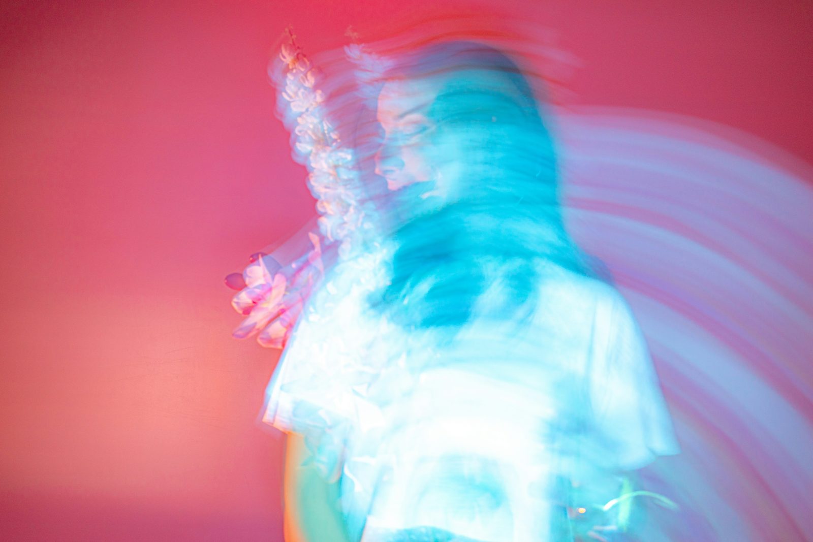 A blurred figure in motion against a pink background