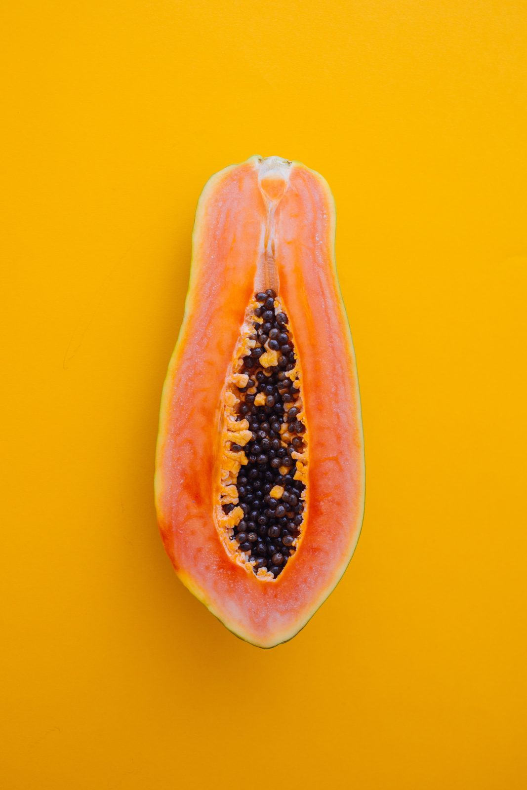 A halved papaya on a yellow background